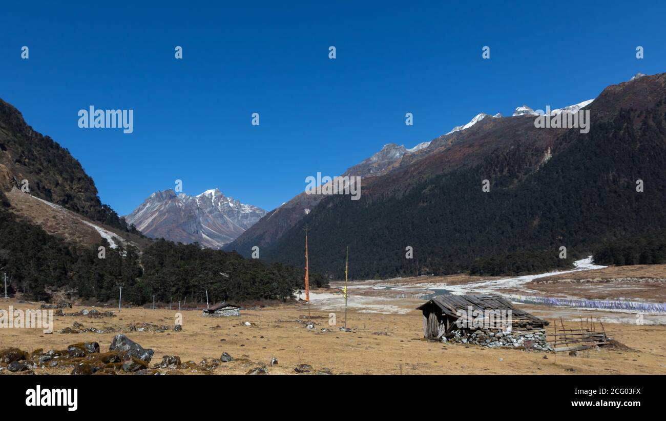 Ein selektives Fokusbild einer Hütte aus Steinen Mit tibetischen Gebetsfahnen vor dem Tal von Blumen in sikkim Indien Stockfoto