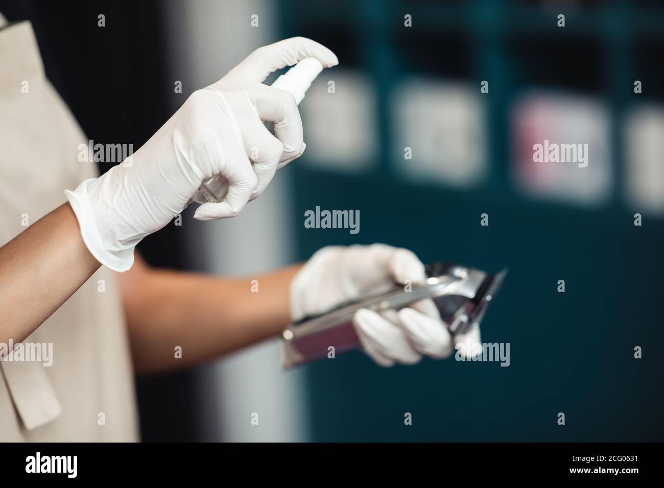 Nahaufnahme der Hände, die Desinfektionsmittel auf den elektrischen Trimmer sprühen Stockfoto