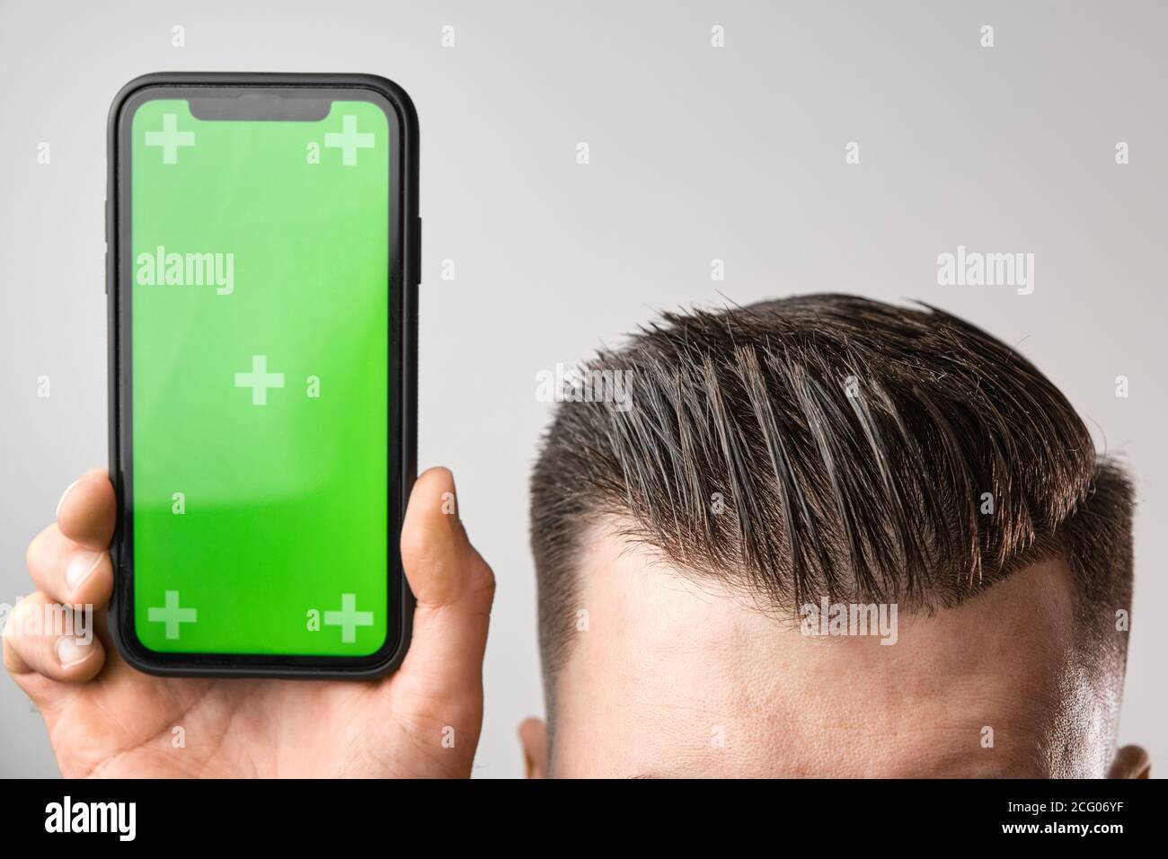 Nahaufnahme eines Smartphones mit einem Chroma-Key in der Nähe von perfektem mans Haarschnitt. Platz für Werbung von Friseurladen kopieren. Stockfoto