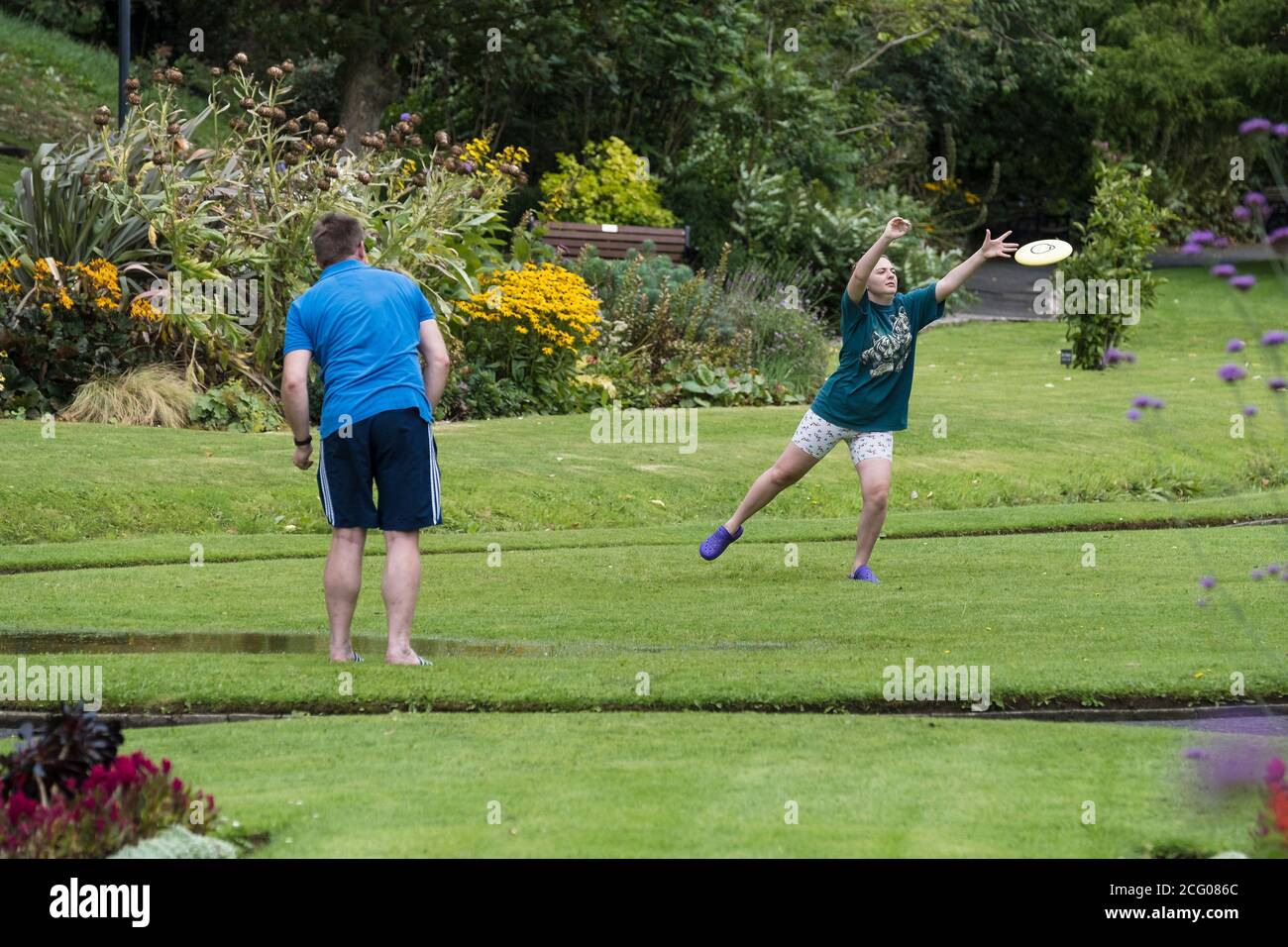 Urlauber spielen mit einem Frisbee in den Trenance Gardens in Newquay in Cornwall. Stockfoto