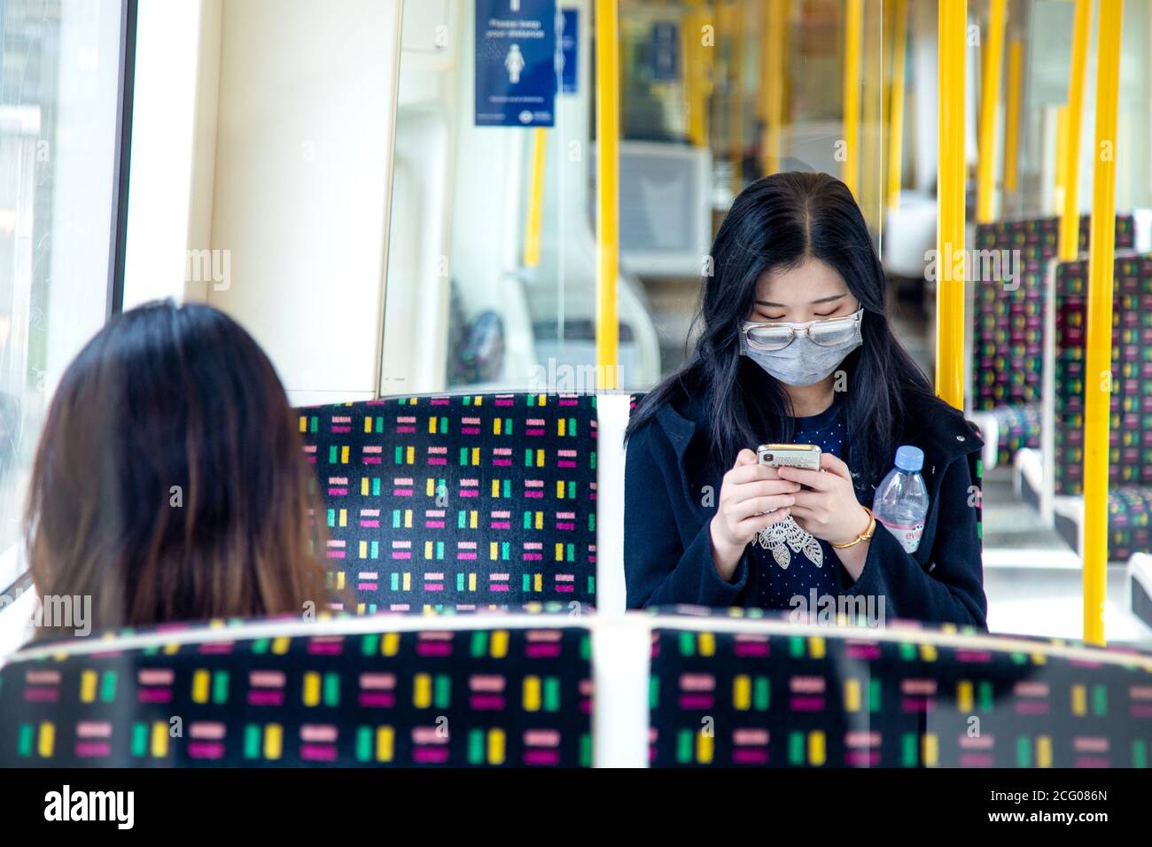 7. September, London, UK - Asiatin sitzt auf der Tube in einem leeren Metropolitan Line Wagen mit Gesichtsmaske während Coronavirus Pandemie Stockfoto