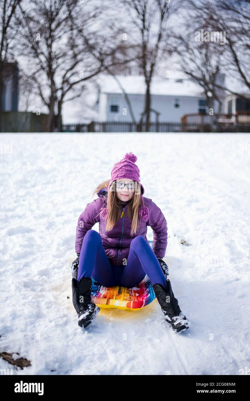 Pre teen sitzt auf Schlitten im Schnee im Winter Stockfoto