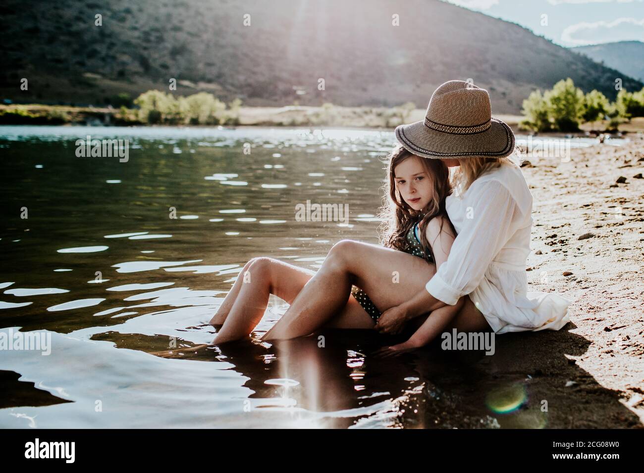 Mutter und Tochter sitzen ruhig im Wasser auf einem Seeufer Stockfoto