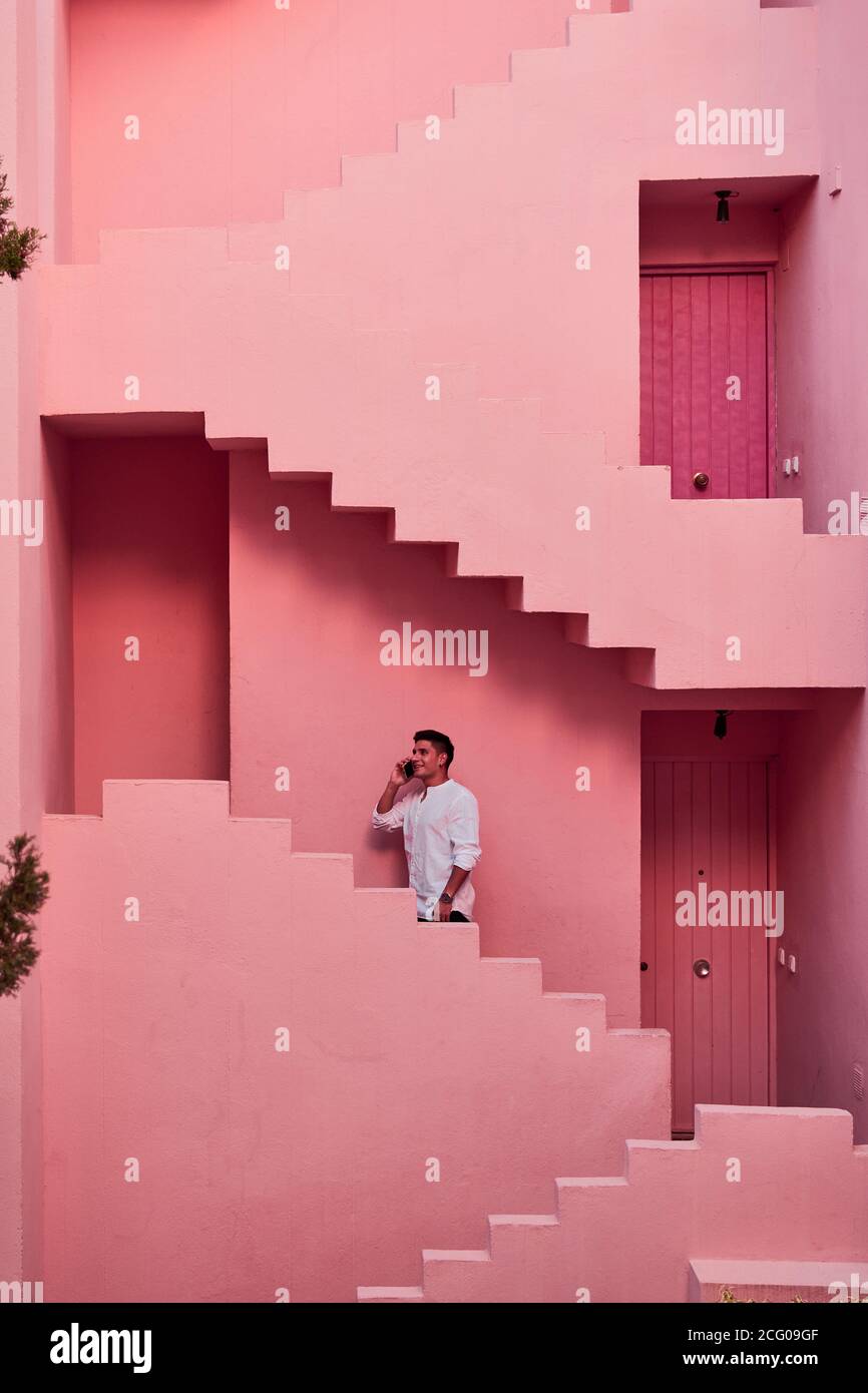 Junger latein spricht auf seinem Handy in rosa Gebäude Stockfoto