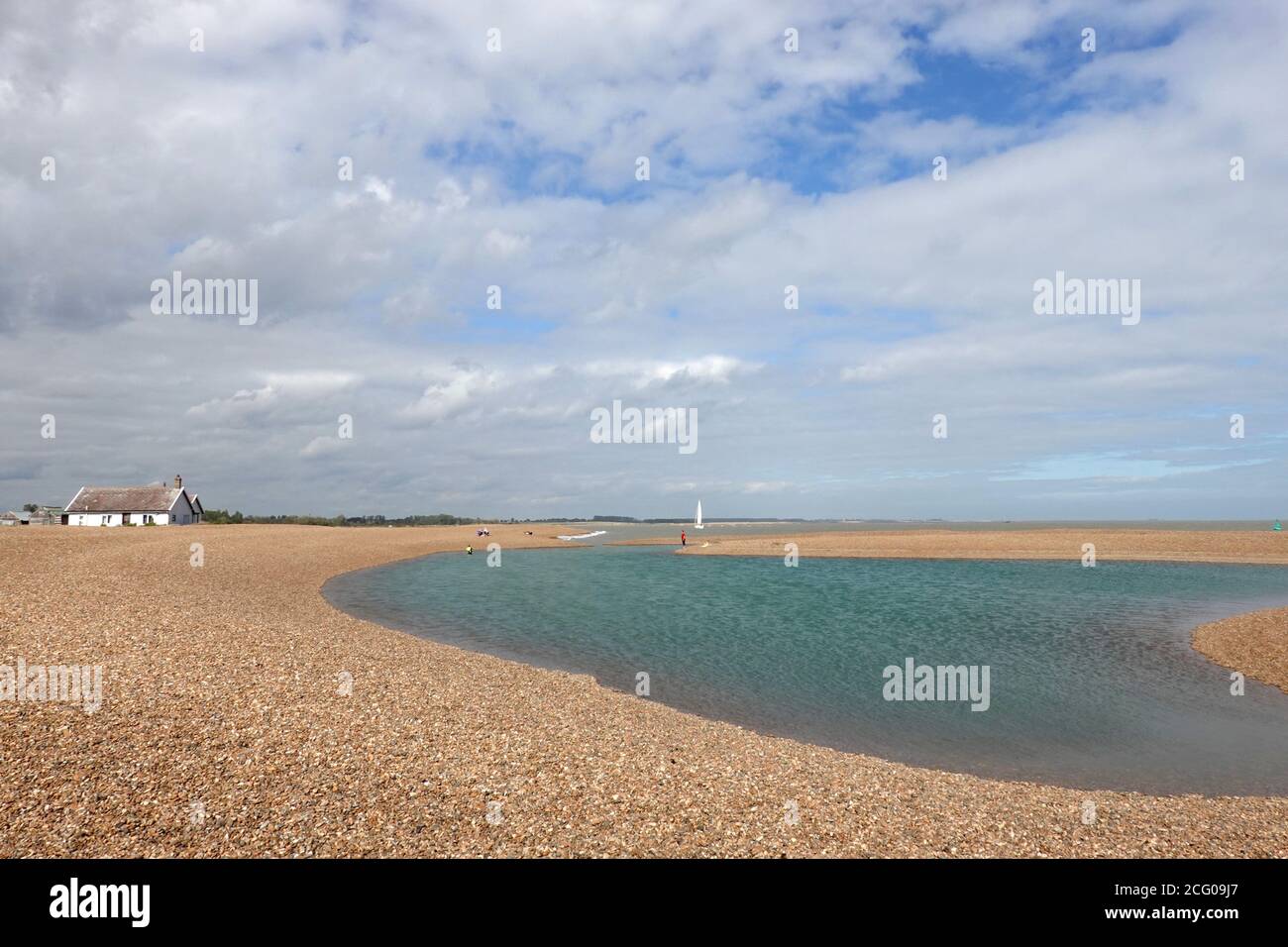 Shingle Street, Suffolk, Großbritannien - 8. September 2020: Weiße Hütten und eine blaue Lagune am steinigen Strand. Stockfoto