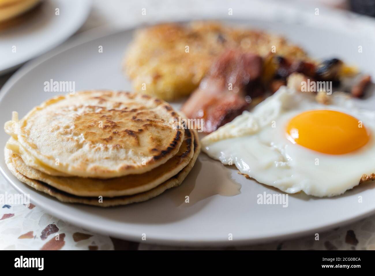 Ein Frühstück mit Eiern, Pfannkuchen, Speck und Kartoffelrösti. Stockfoto