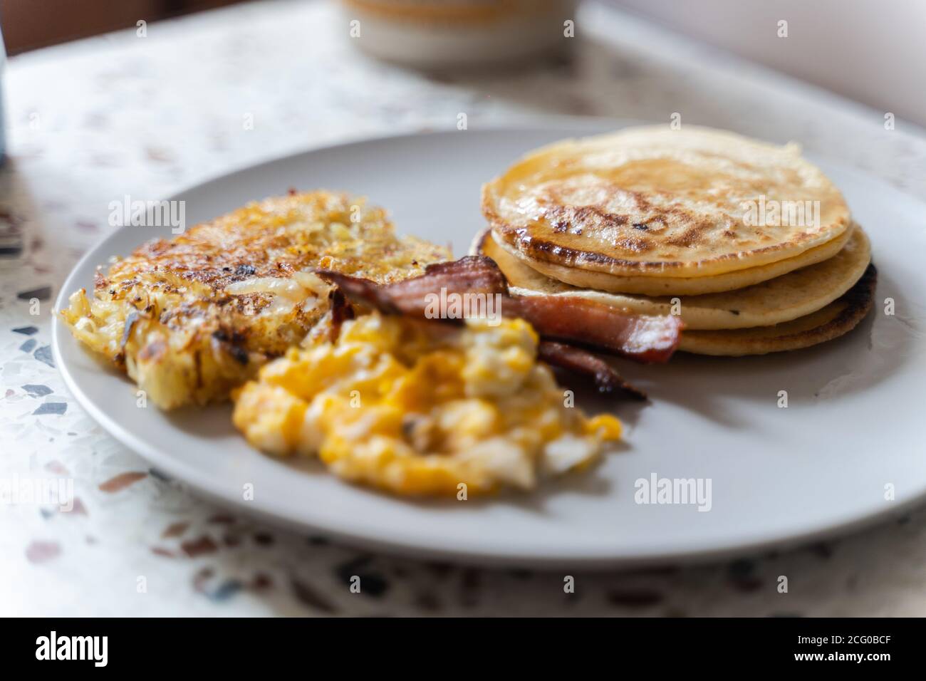 Ein Frühstück mit Eiern, Pfannkuchen, Speck und Kartoffelrösti. Stockfoto