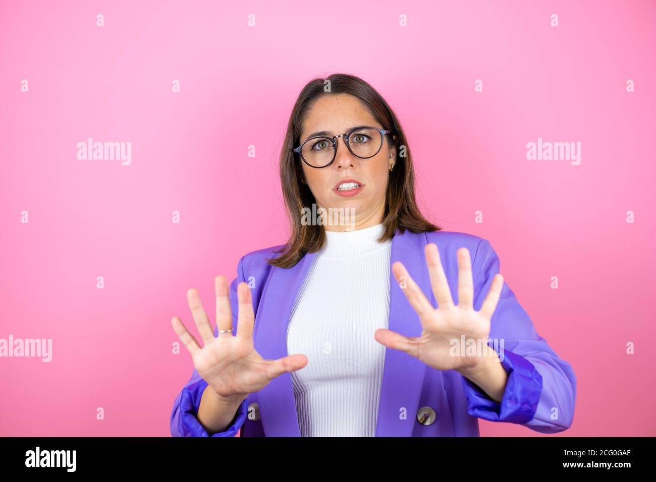 Junge schöne Geschäftsfrau über isolierten rosa Hintergrund Angst und erschrocken vor Angst Ausdruck Stop Geste mit Händen, schreien im Schock. Schwenken Stockfoto