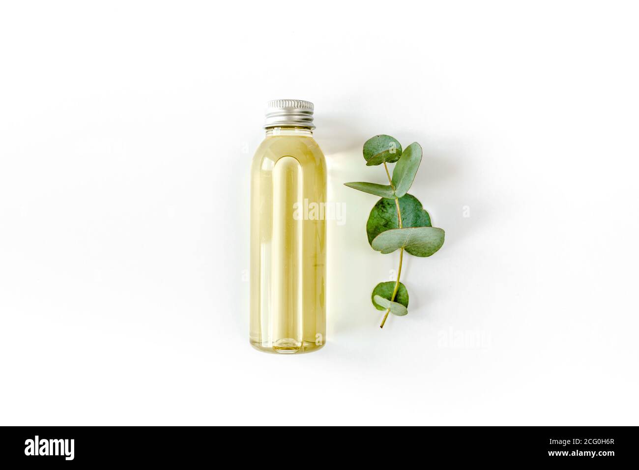 Flasche ätherisches Eukalyptusöl, Eukalyptusblätter auf weißem Hintergrund. Natürliche, organische Kosmetikprodukte. Flach liegend, Draufsicht. Stockfoto