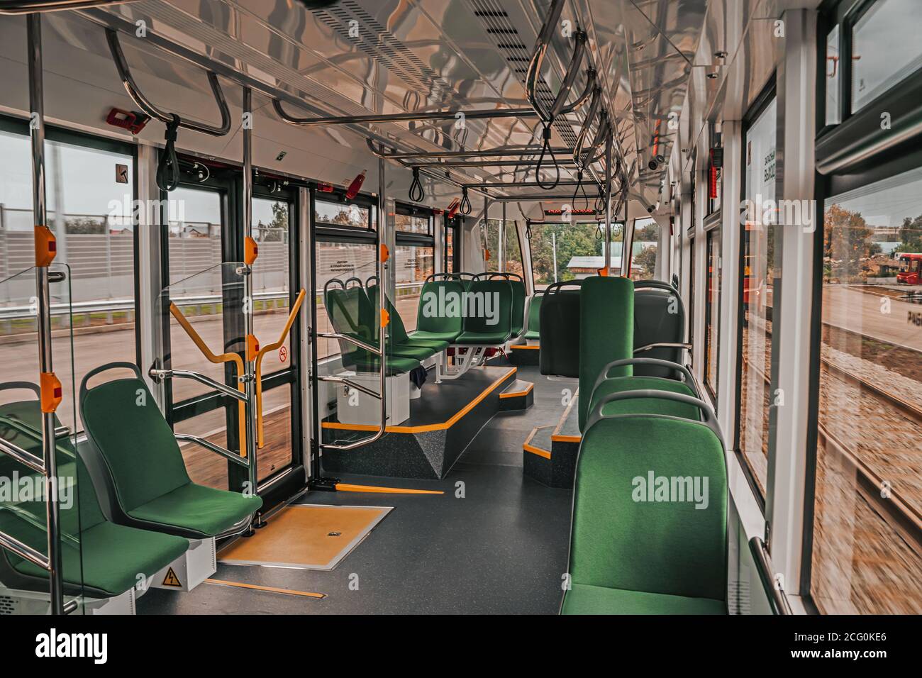 Innenarchitektur einer modernen Straßenbahn. Leeres Straßenbahninnere. Öffentliche Verkehrsmittel in der Stadt. Personenbeförderung. Straßenbahn mit grünen Sitzen und Metallgeländern. Stockfoto