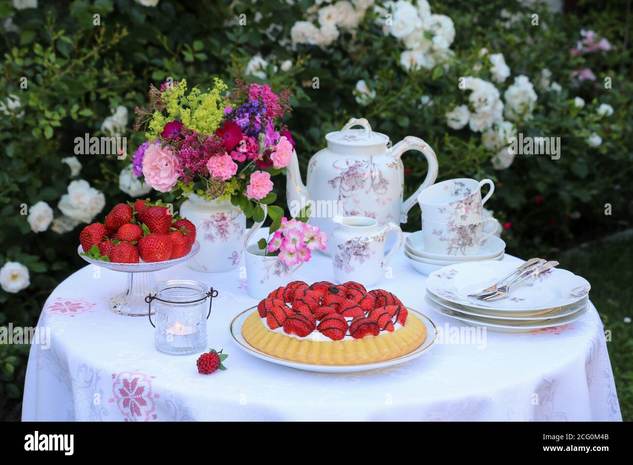 Tischdekoration mit Erdbeerkuchen, Vintage Porzellan und Blumenstrauß Stockfoto