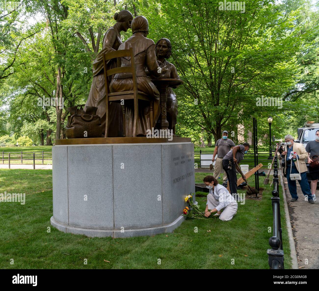 Die Künstlerin Meredith Bergmann arrangiert Blumen vor ihrem Women’s Rights Pioneer Monument als Parks Dept. Arbeiter beenden die Installation auf dem Literary Walk im Central Park in New York am Tag ihrer Enthüllung, Mittwoch, 26. August 2020. Die Statue, von links nach rechts, von Sojourner Truth, Susan B. Anthony und Elizabeth Cady Stanton erinnert an den 100. Jahrestag der 19. Änderung, die Frauen das Wahlrecht gab. Der Bildhauer Meredith Bergmann ist das einzige Denkmal im Central Park, das echte Frauen darstellt. (© Richard B. Levine) Stockfoto