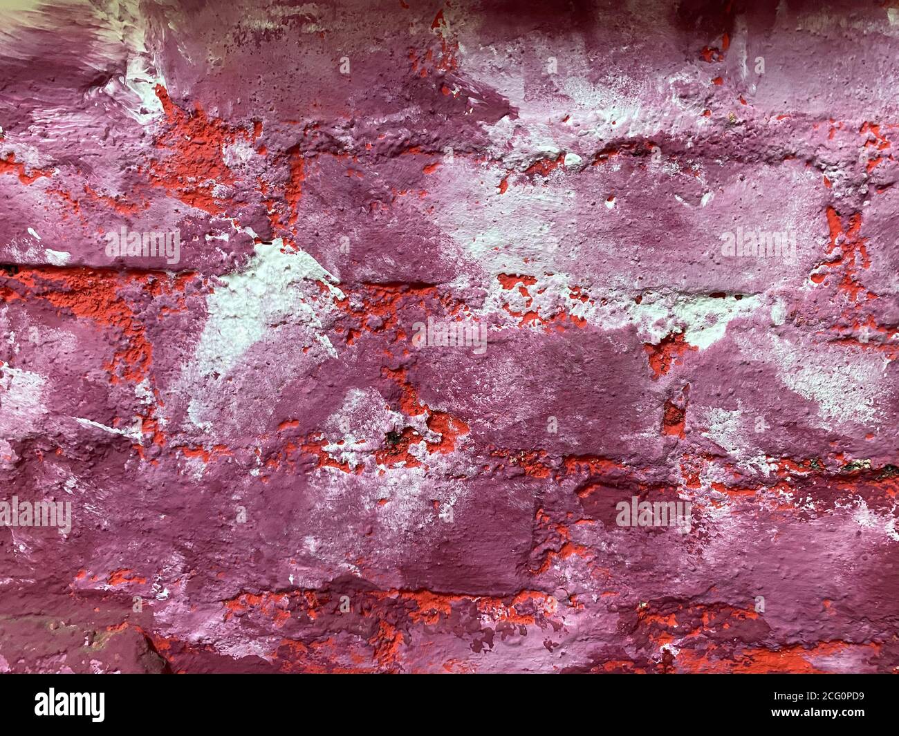 Blick auf isolierte raue Ziegelwand in weiß, rosa, lila und weiß lackiert Stockfoto