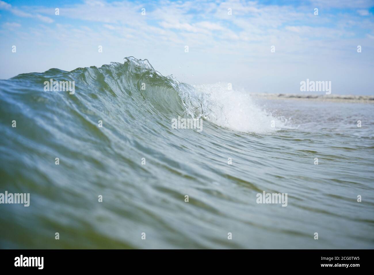 Eine azurblaue Meereswelle mit einem weißen Kamm läuft an Land. Stockfoto