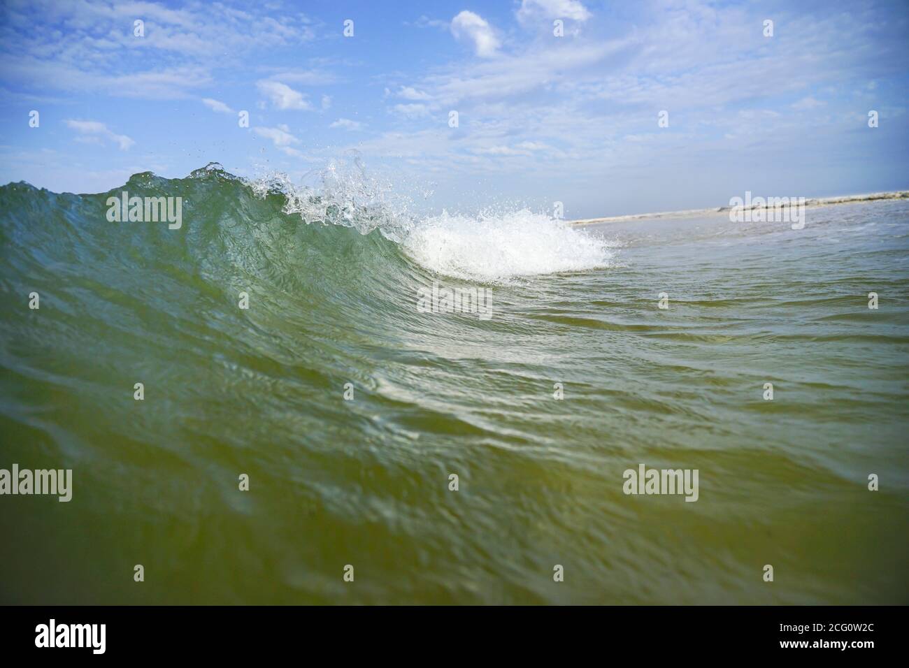 Eine azurblaue Meereswelle mit einem weißen Kamm läuft an Land. Stockfoto
