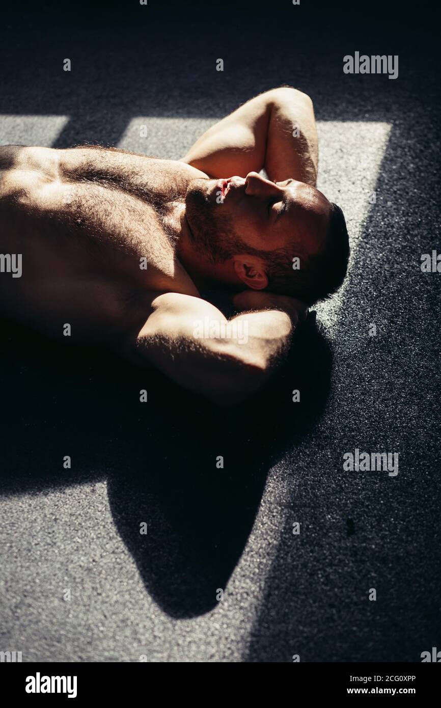 Innenaufnahme des Fitness-Männchens, das im Fitnessstudio trainiert. Muskulöser junger Mann macht Bauchübungen. Stockfoto