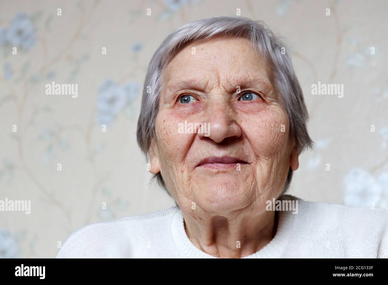 Ältere Frau mit friedlichem Ausdruck dachte über etwas nach. Glückliche Frau mit grauen Haaren und faltiger Haut, Konzept der Erinnerungen, Alter Stockfoto