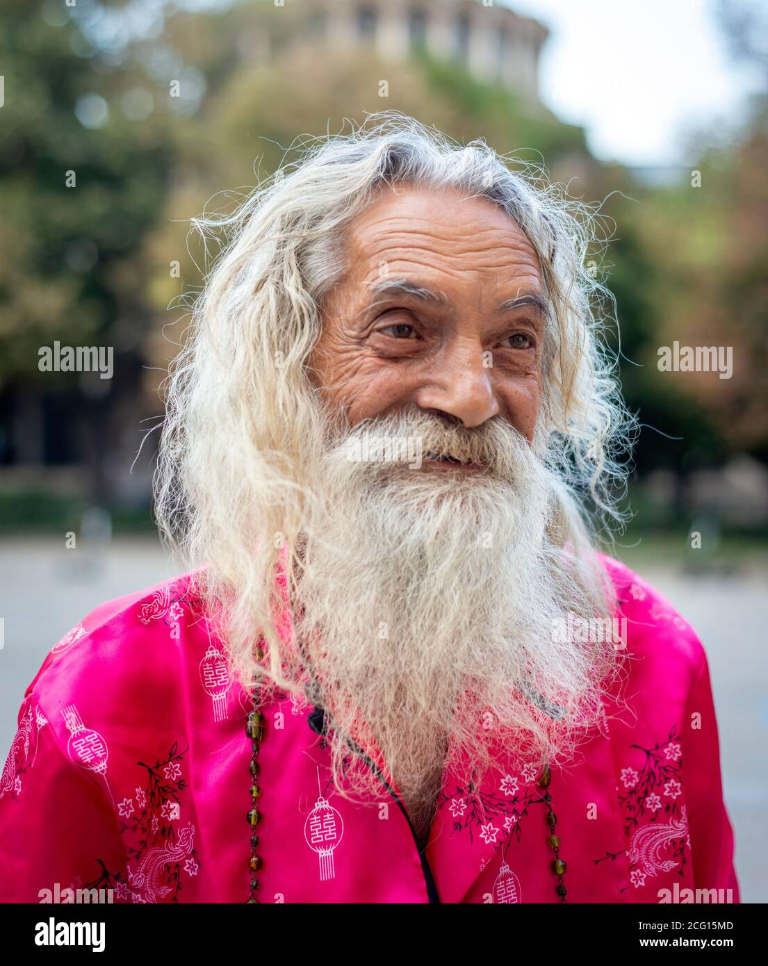 Seniorenporträt eines lächelnden, extravaganten bärtigen Mannes mit langen weißen Haaren in rosa Kleidung auf den Straßen von Sofia Bulgarien, Osteuropa, EU Stockfoto