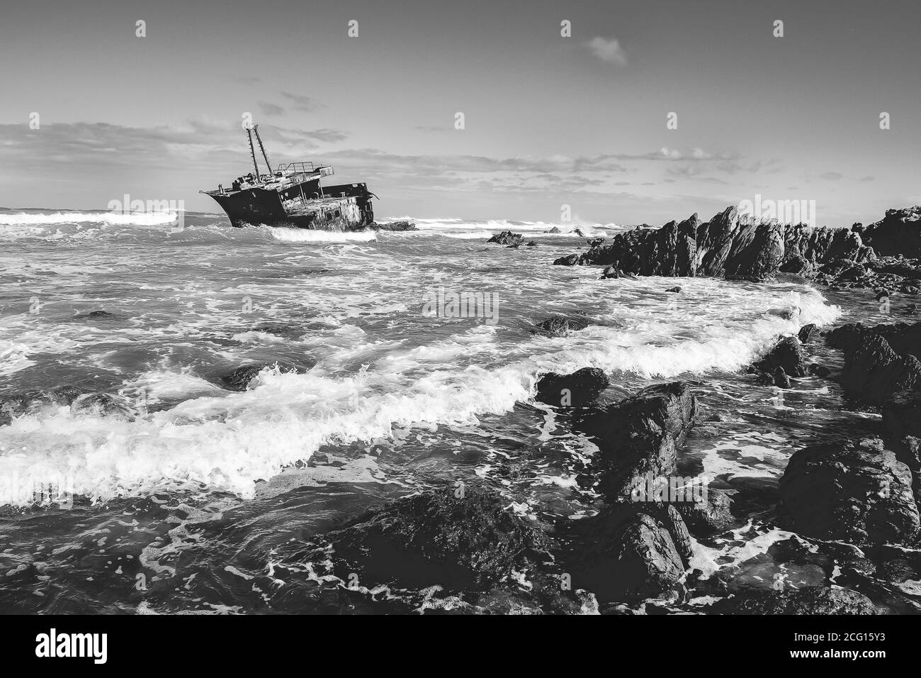 Altes verwittertes Schiffswrack in Untiefen mit Wellen, felsige Küste von L'Agulhas, Südafrika Stockfoto