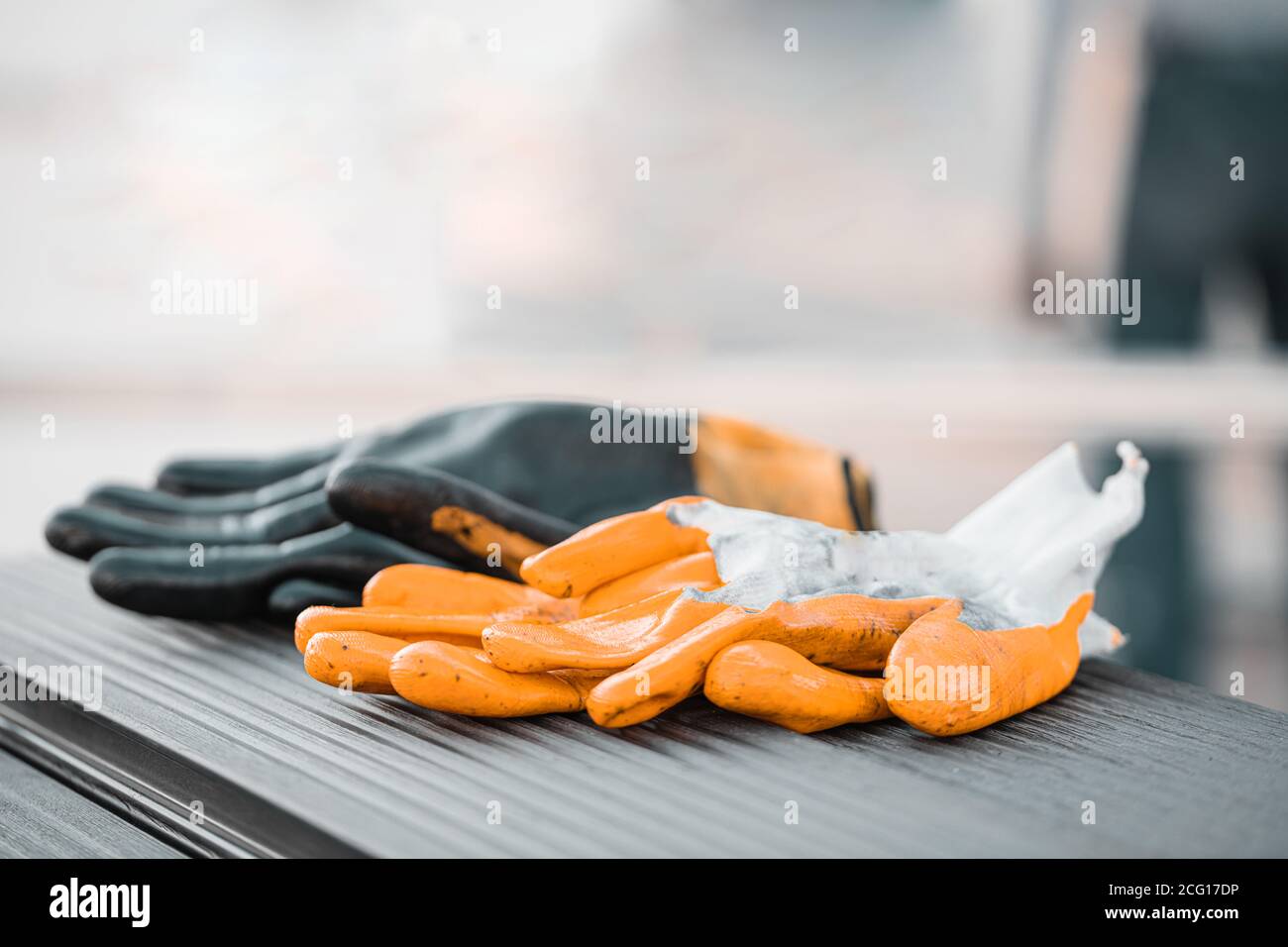 Gelbe und schwarze Schutzhandschuhe auf anthrazitfarbenem Composite Deck Hintergrund Stockfoto