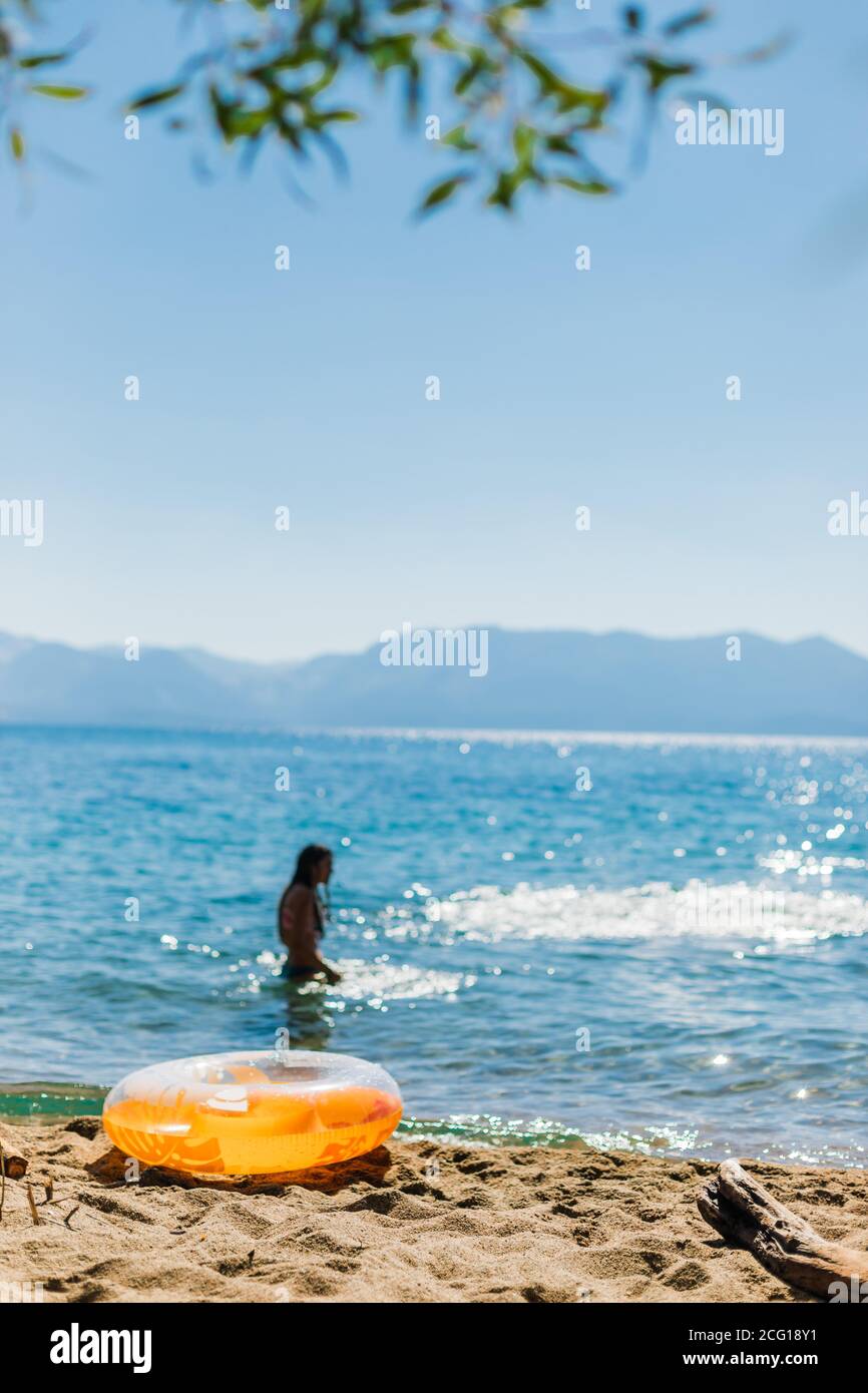 Schwimmer in einem Bergsee mit Blättern und Orange Ring Stockfoto