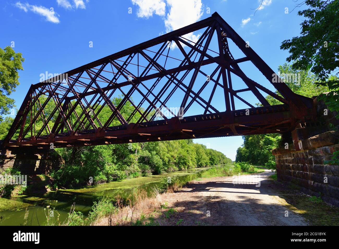 Sheffield, Illinois, USA. Eine aktive Eisenbahnbrücke überspannt einen Abschnitt des Hennepin-Kanals und dessen angrenzenden Weg. Stockfoto