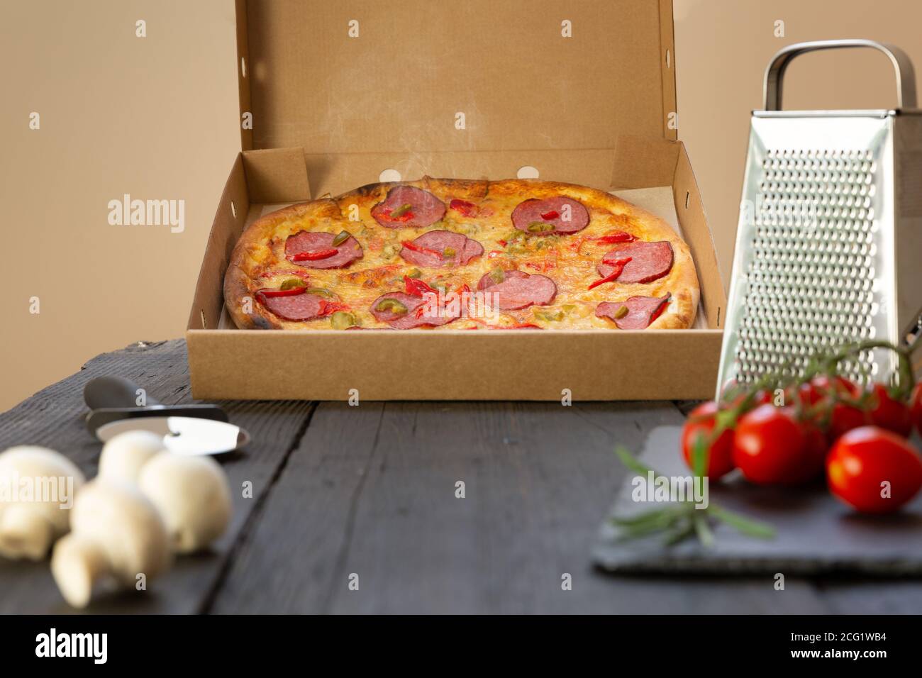 Heiße Pizza und Zutaten auf einem schwarzen Tisch Stockfoto