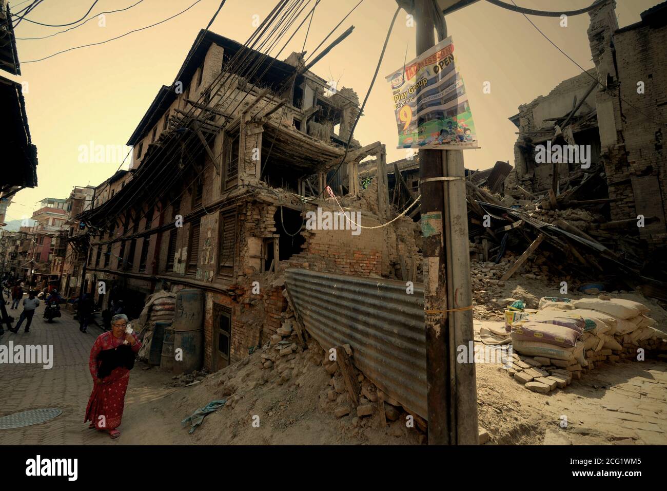 Ein älterer Bürger, der auf einer Wohnallee läuft, in der Gebäude, die durch die Erdbeben von 2015 schwer beschädigt wurden, in Bhaktapur, Nepal, liegen. Stockfoto