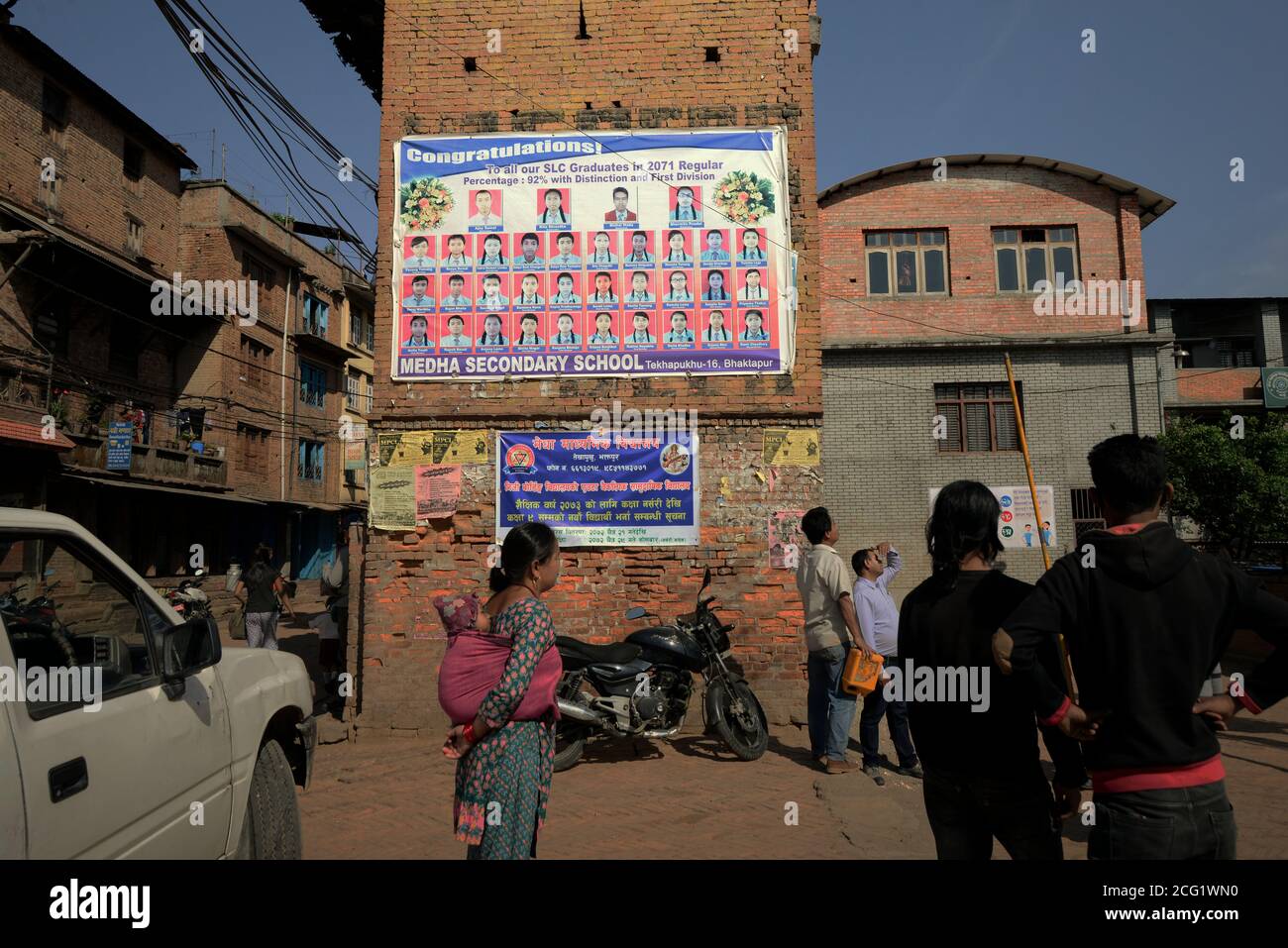 Menschen, die vor einem Abschlussplakat auf dem Vorhof eines Gymnasiums in Bhaktapur, Nepal, stehen. Stockfoto
