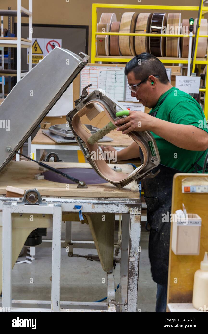 Arbeiter beim Bau und Zusammenbau von Gitarren in der Taylor Guitar Fabrik in Tecate, Mexiko. Dieser Arbeiter klebt die Hälften des Gitarrenkörpers zusammen. Stockfoto