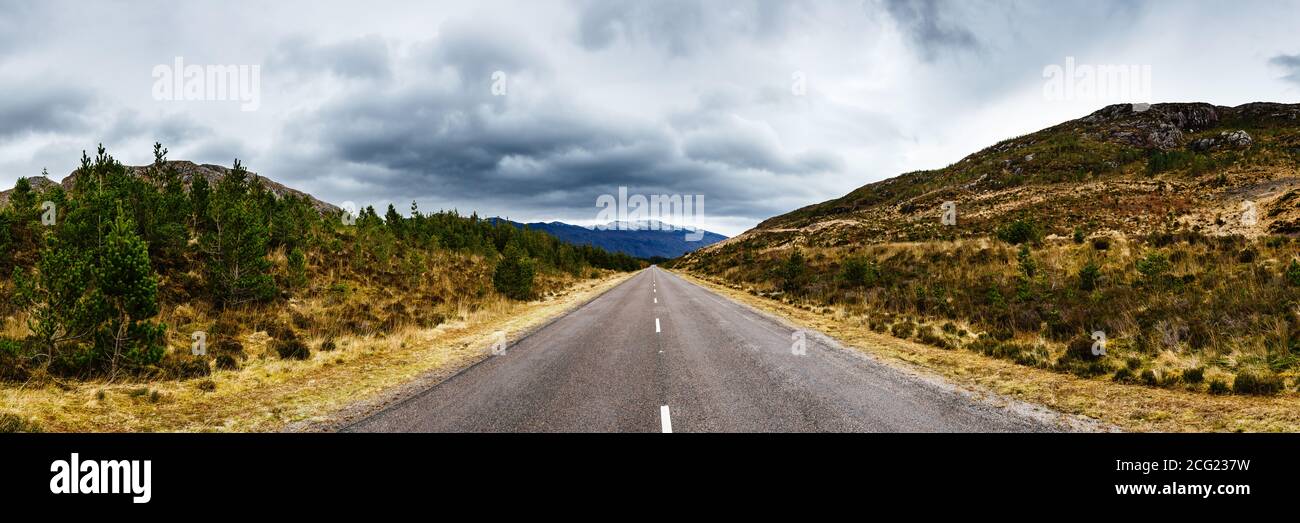 Straße unter dem bewölkten Himmel zwischen zwei Hügeln, irgendwo in Highlands, Schottland Stockfoto