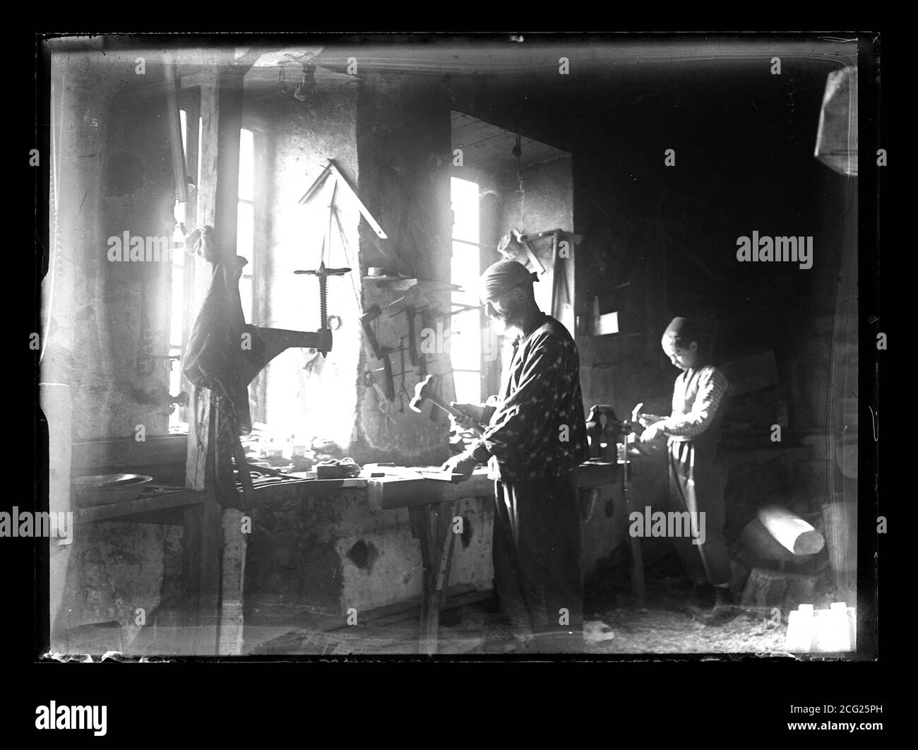 Westtürkei in oder bei Smyrna (Izmir) etwa 1910 Handwerker mit Lehrling, der in der Werkstatt mit Hammer arbeitet. Fotografie auf trockenem Glasplatte aus der Sammlung Herry W. Schaefer, um 1910. Stockfoto