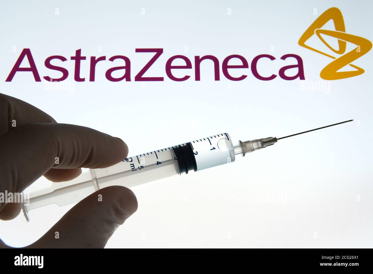 Impfstoffkonzept von AstraZeneca Oxford. Spritze auf einem weißen Bildschirm und AstraZeneca Logo auf dem unscharfen Hintergrund. Stockfoto
