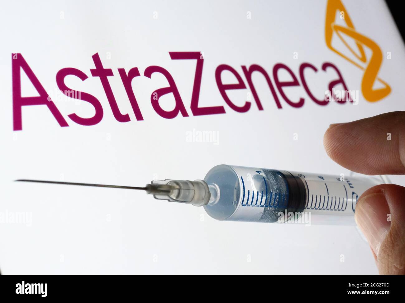Impfstoffkonzept von AstraZeneca Oxford. Spritze auf einem weißen Bildschirm und AstraZeneca Logo auf dem unscharfen Hintergrund. Stockfoto