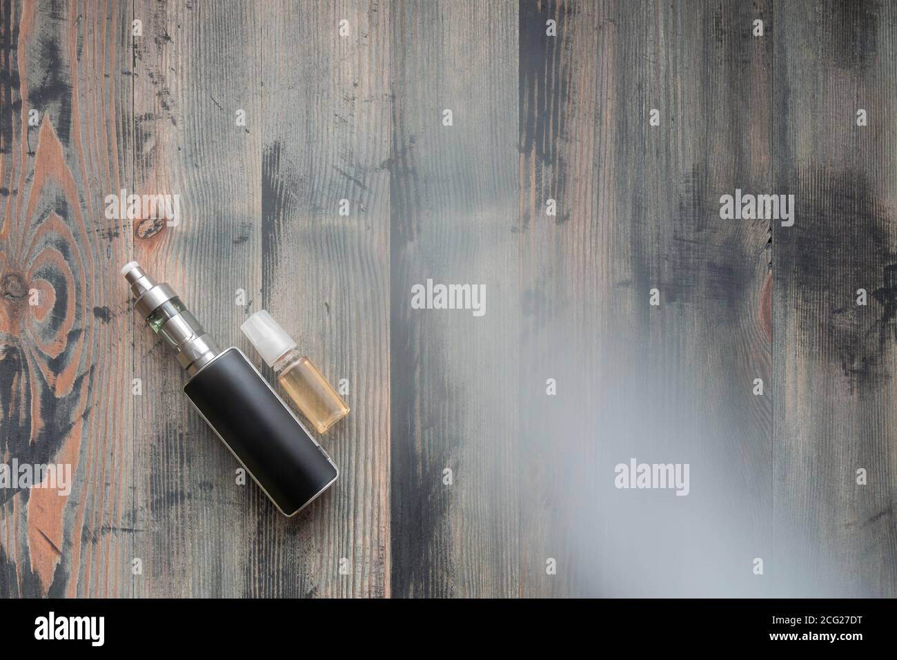 Schwarze E-Zigarette und süßes E-Liquid auf grauem Holzhintergrund, verdeckter Rauch. Draufsicht. Alternative zu Tabak. Stockfoto