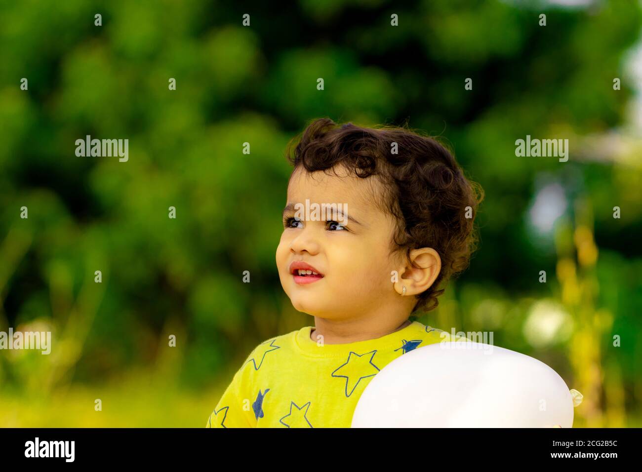 Ein schönes kleines indisches Kind ist glücklich mit einem weißen Ballon in den Händen, asiatische Kinder Stockfoto