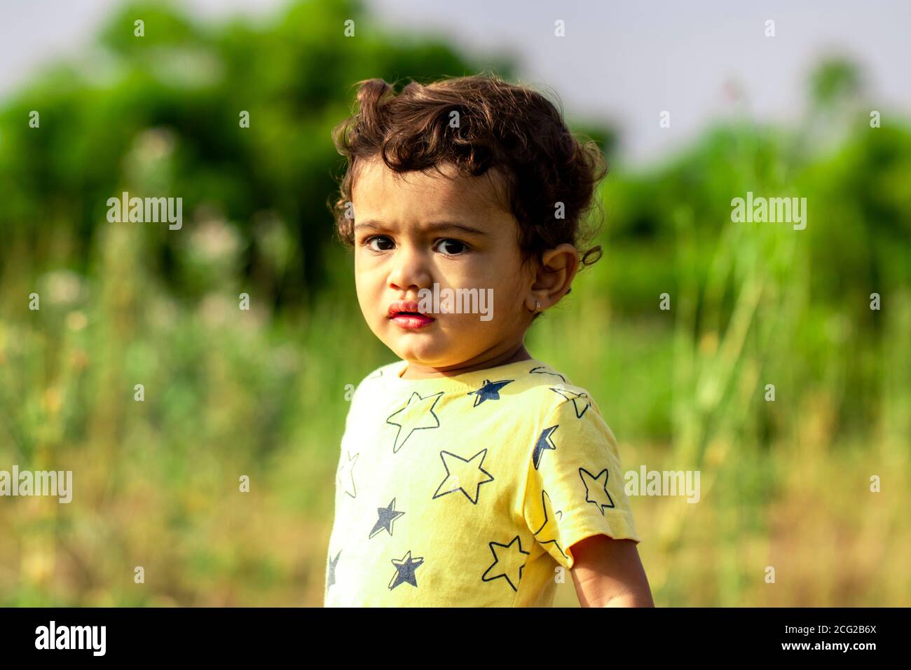 Ein trauriges kleines indisches Kind, das wütend auf die Kamera schaut, asiatische Kinder in der Natur Stockfoto