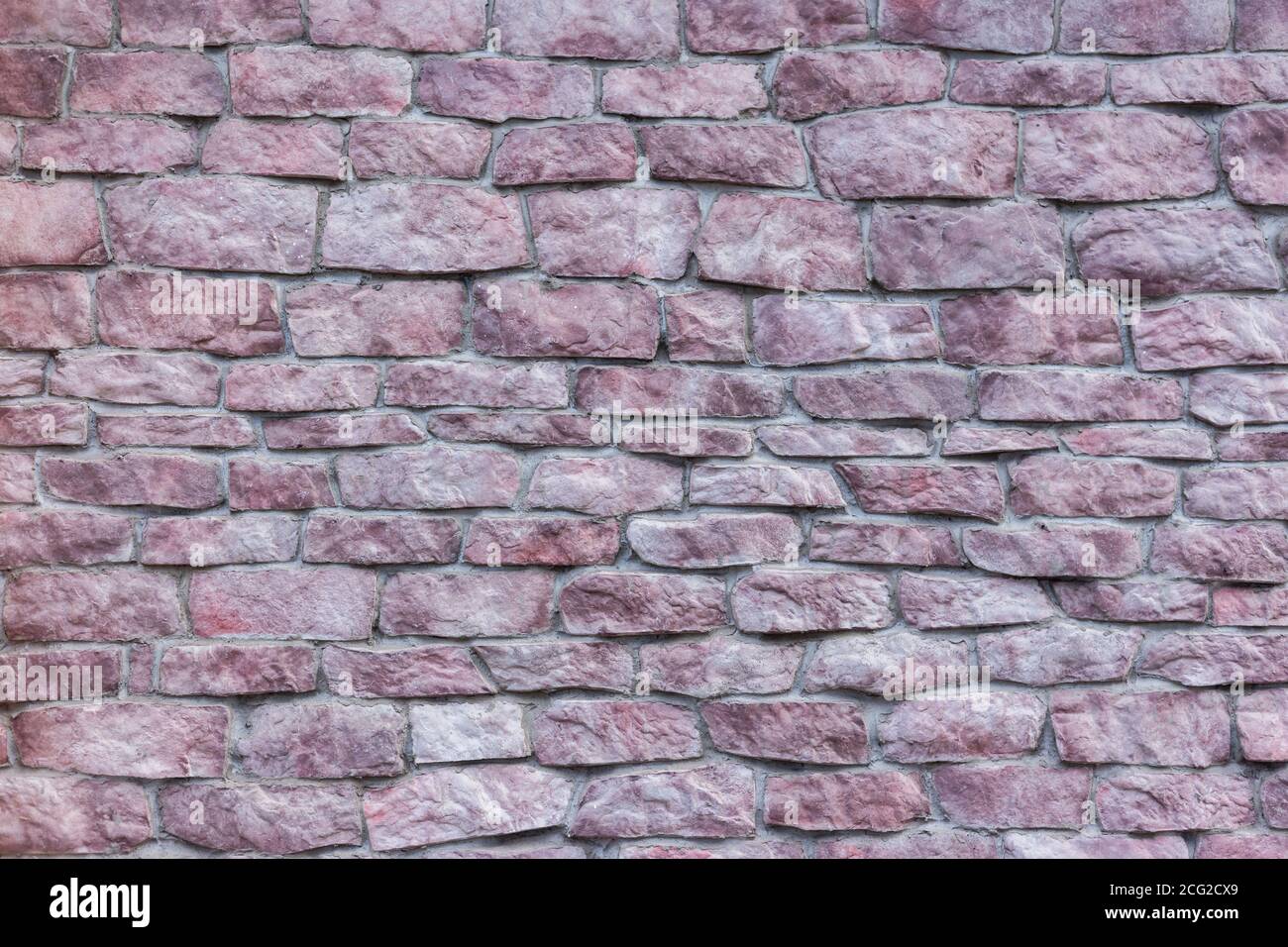 Eine Wand aus rosa Stein. Die alte Mauer. Stockfoto