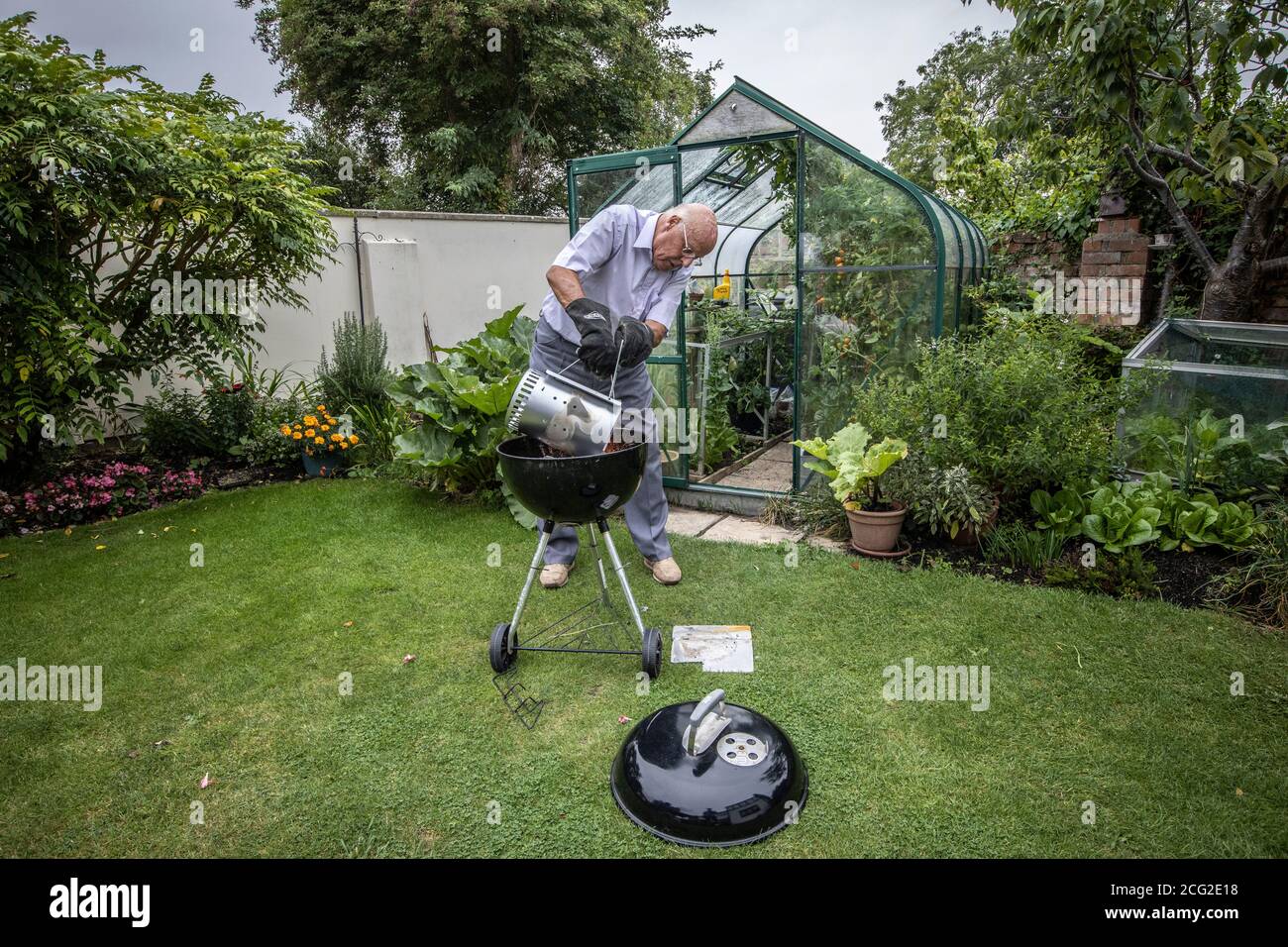 Rentnerpaar in den 80er Jahren genießen das Leben im Freien Grillen und Essen gesundes Gemüse aus eigenem Anbau während der Coronavirus Lockdown, Somerset, Großbritannien Stockfoto