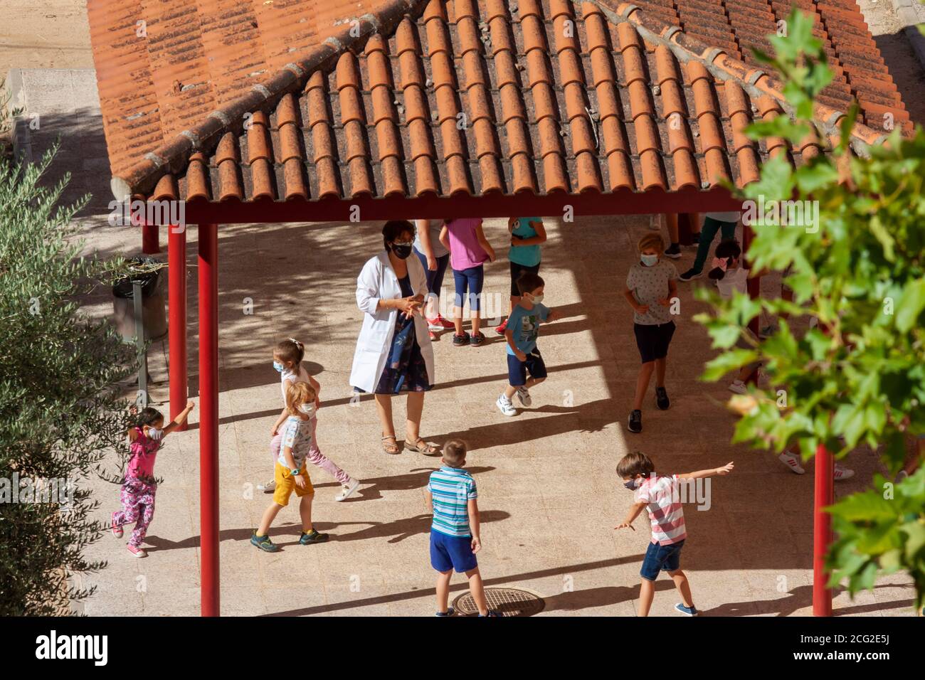 Toledo, Spanien. September 2020. Während der COVID-19-Pandemie hat eine Grundschullehrerin die Kinder während der Spielzeit auf dem Spielplatz im Auge. Stockfoto