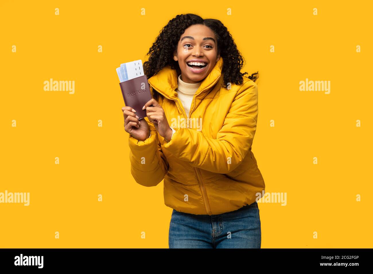 Black Girl Zeigt Tickets Going On Winter Vacation, Gelber Hintergrund Stockfoto