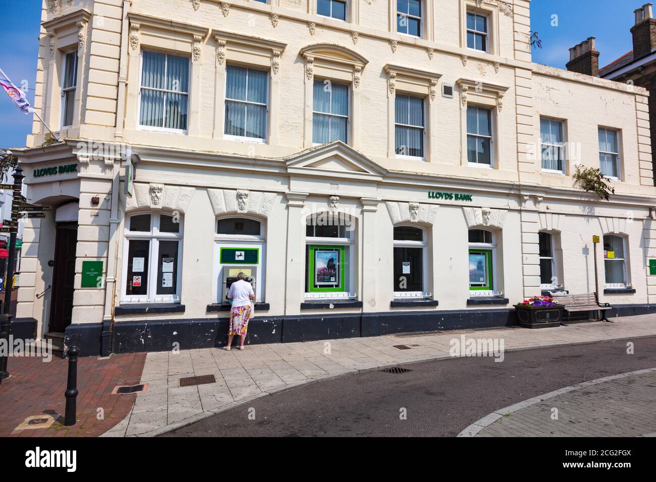Eine Frau zieht Bargeld von einem Geldautomaten in Lloyds Bank Gebäude in Sandwich, Kent, Großbritannien Stockfoto