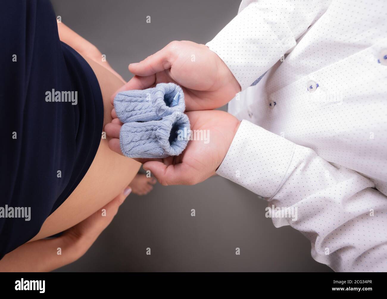 Cute Nahaufnahme der Herzform eines Paares Hände zusammen auf der schwangeren Frau Bauch. Selektiver Fokus. Stockfoto