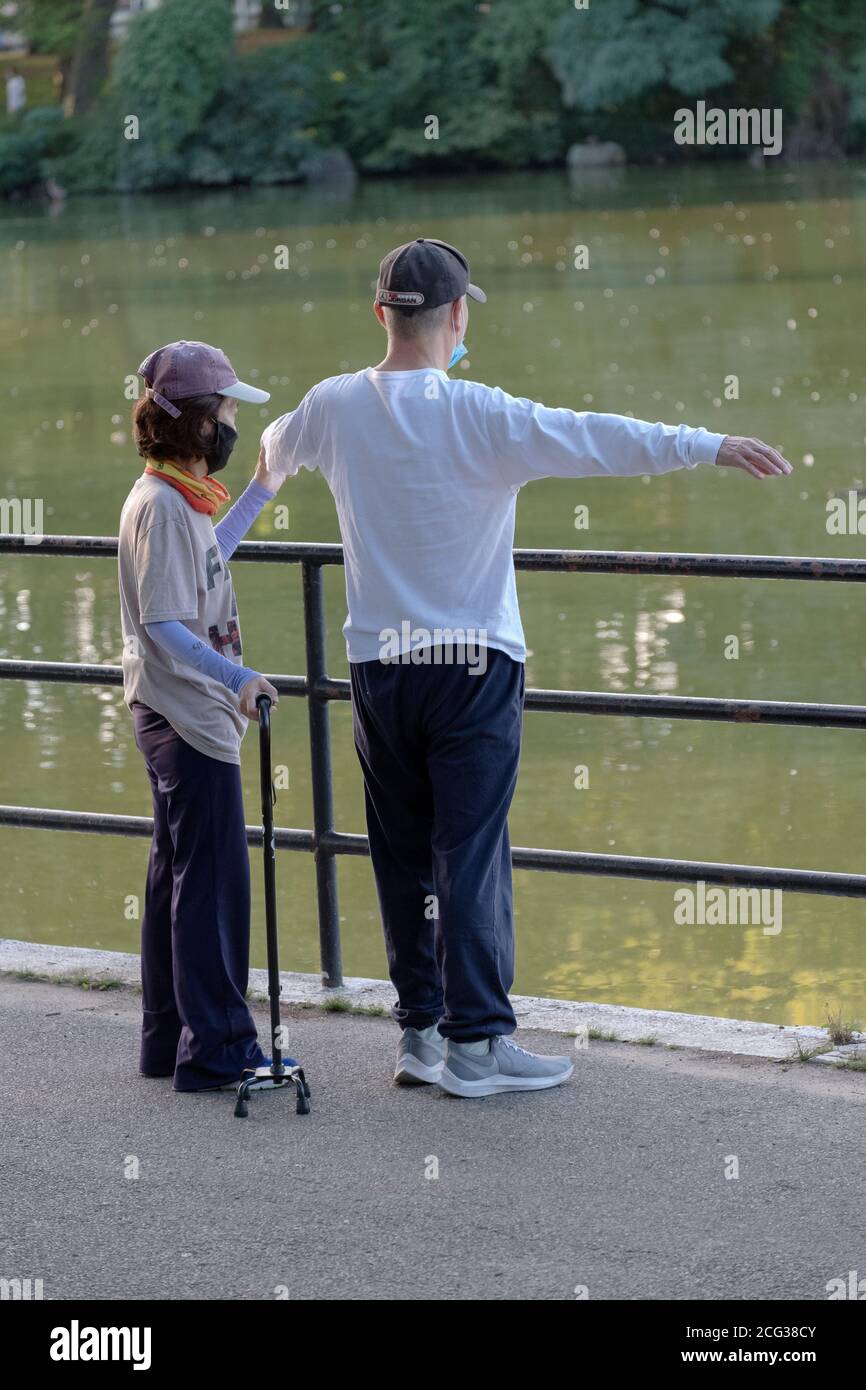 Ein Helfer hilft einem Mann mit gesundheitlichen Problemen, seine Stretching-Routine zu tun. In einem Park in Flushing, Queens, New York City. Stockfoto