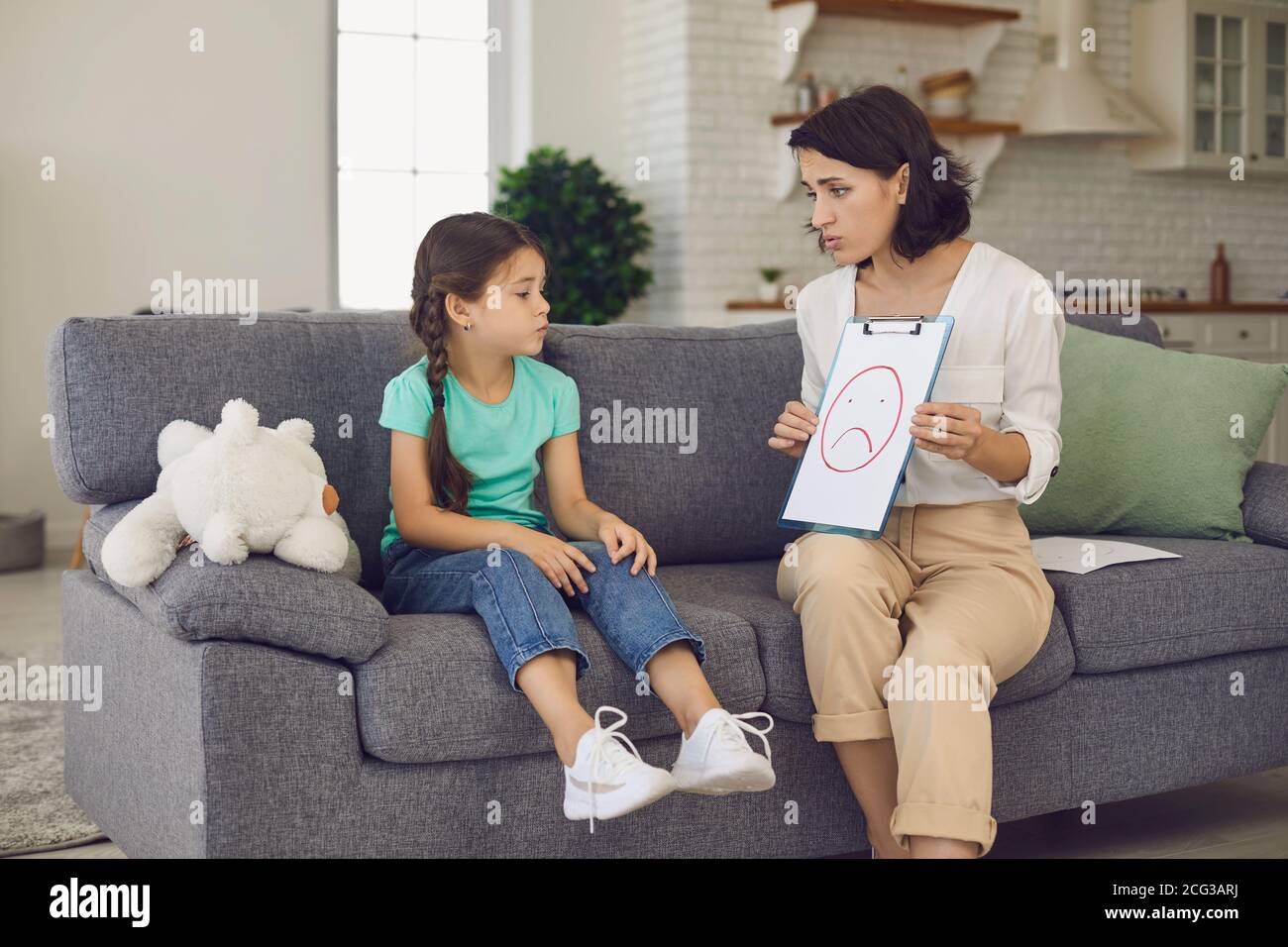 Das kleine Mädchen schaut auf ein Bild, das ihr ein Kinderpsychologe an ihrem Empfang zeigt. Stockfoto