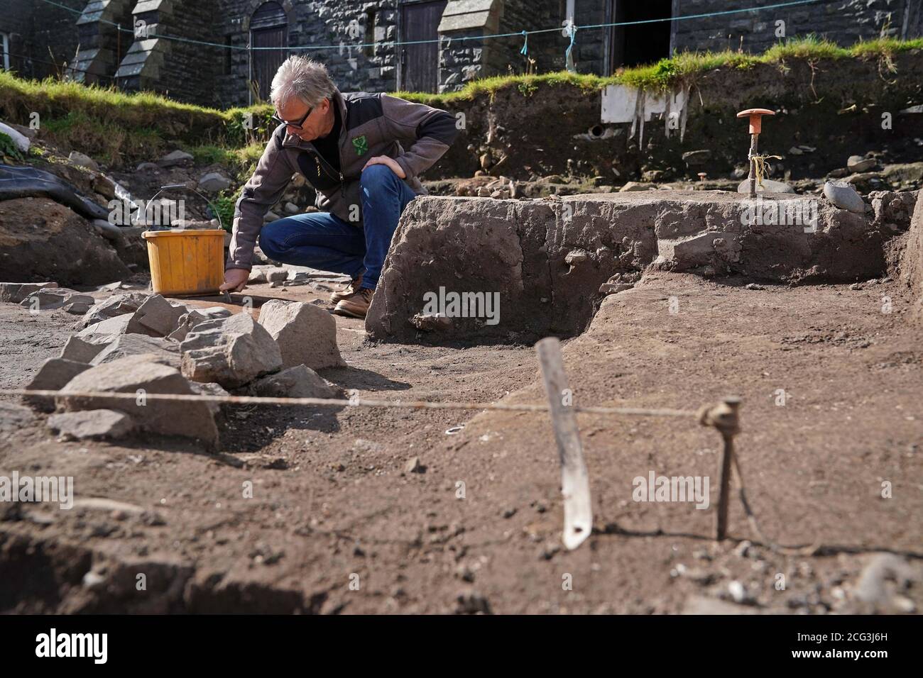 Graeme Young, Archäologe und Direktor des Bamburgh Research Project, in Bamburgh Castle, Northumberland, wo Freiwillige die Grundlagen eines seltenen Rundhauses gefunden haben, das über 2000 Jahre alt sein könnte. Die Freiwilligen, die ihr jährliches Feldprojekt auf der Burg beendeten, entschieden sich in letzter Minute, noch ein paar Zentimeter Boden auszugraben und enthüllten die Fundamente eines "substantialen" Rundhauses mit einem Durchmesser von etwa 12 Metern. Es wird angenommen, dass die ursprüngliche Struktur über 2000 Jahre alt sein könnte, aus der römischen Besetzung von Großbritannien, und halten wichtige Hinweise auf den Übergang von der Rom Stockfoto