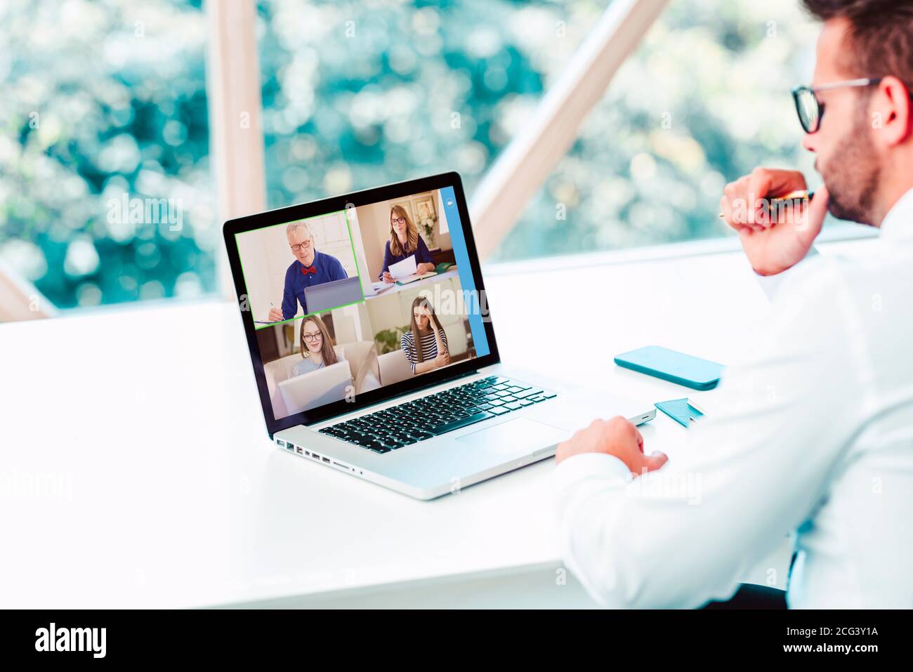 Rückansicht des Geschäftsmannes, der hinter seinem Laptop sitzt und Diskussion und Online-Meeting in Videoanruf hat. Stockfoto