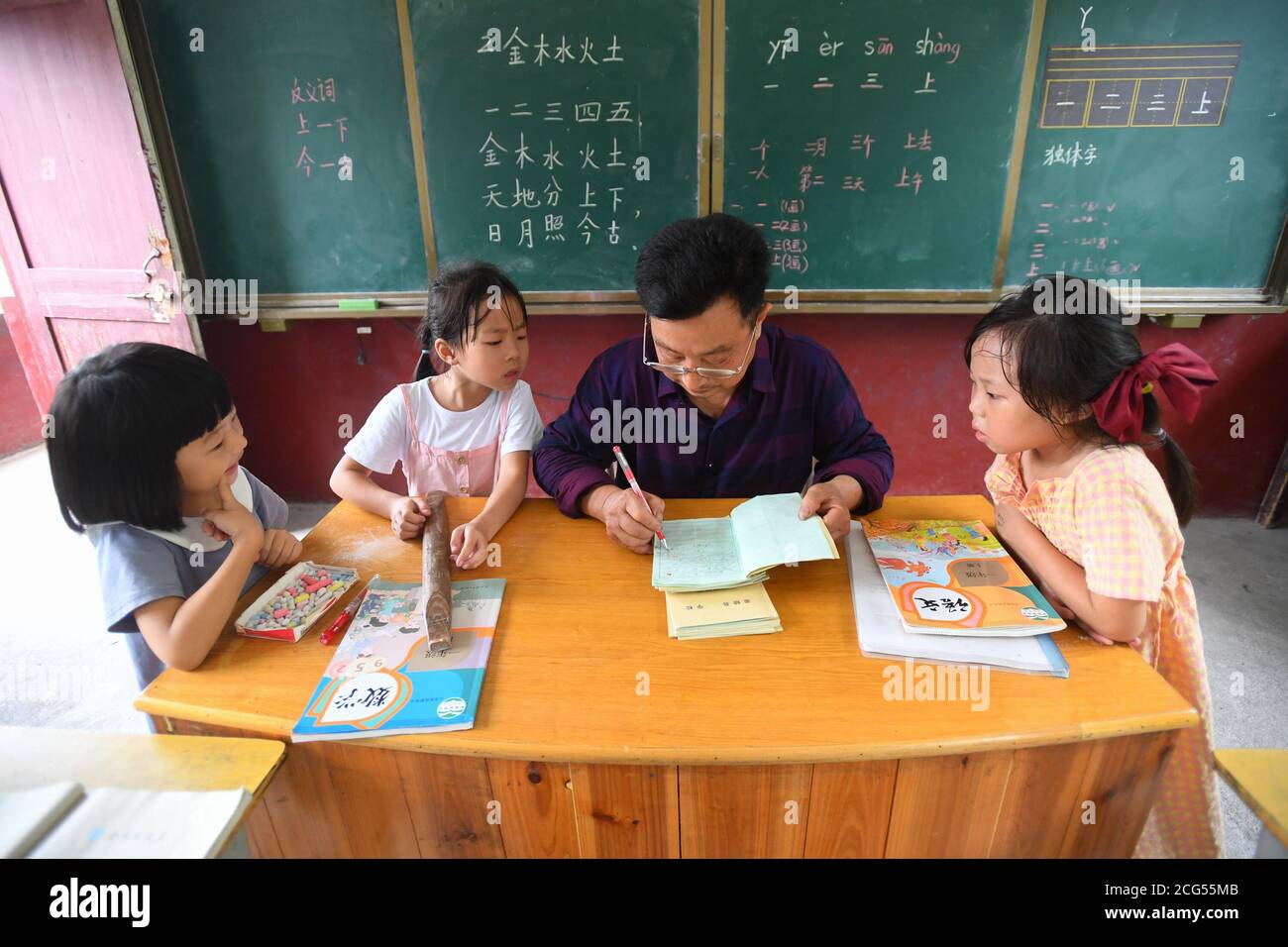 (200909) -- CHANGSHA, 9. September 2020 (Xinhua) -- Dong Zhuwen (2. R) markiert die Hausaufgaben seiner Schüler in einer chinesischen Klasse an der Chagan Grundschule in der Gemeinde Huju im Bezirk Chaling, Provinz Hunan in Zentralchina, 8. September 2020. Dong Zhuwen, 63, ist Lehrer für Schüler der ersten und zweiten Klasse an der Chagan Primary School. Geboren in Huju Township, begann Dong Zhuwen seine Lehrtätigkeit hier im Jahr 1977. Nach seiner Pensionierung im Jahr 2017, entschied er sich für den Aufenthalt in der Schule und weiterhin Unterricht, da die Schule war in Mangel an Lehrern. "Ich mag Kinder, ich möchte für sie bleiben", sagte Dong. Er hofft auch, dass mehr Stockfoto