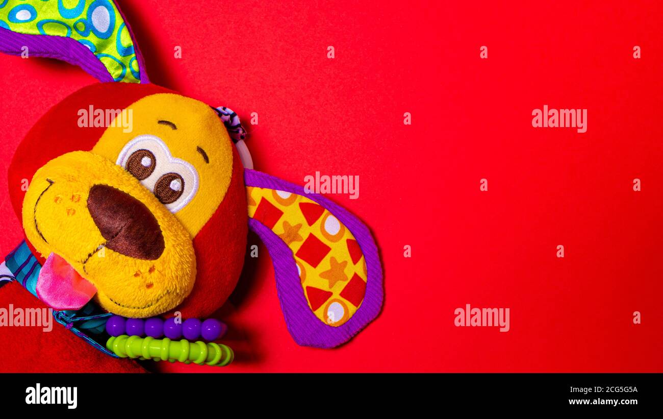 Rot orange doggy Spielzeug auf einem roten Hintergrund mit Platz für Text. Weiches Plüsch Spielzeug für Baby Hund Banner für Spielzeugladen. Stockfoto