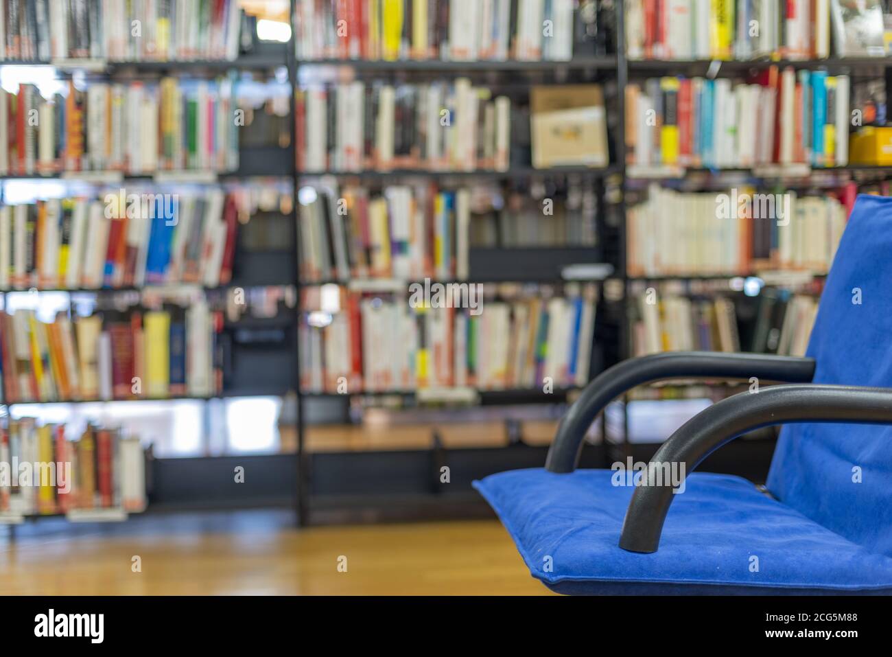 Öffentliche Bibliothek innen mit unbesetzten blauen Sessel und viele Bücher in den Regalen Stockfoto